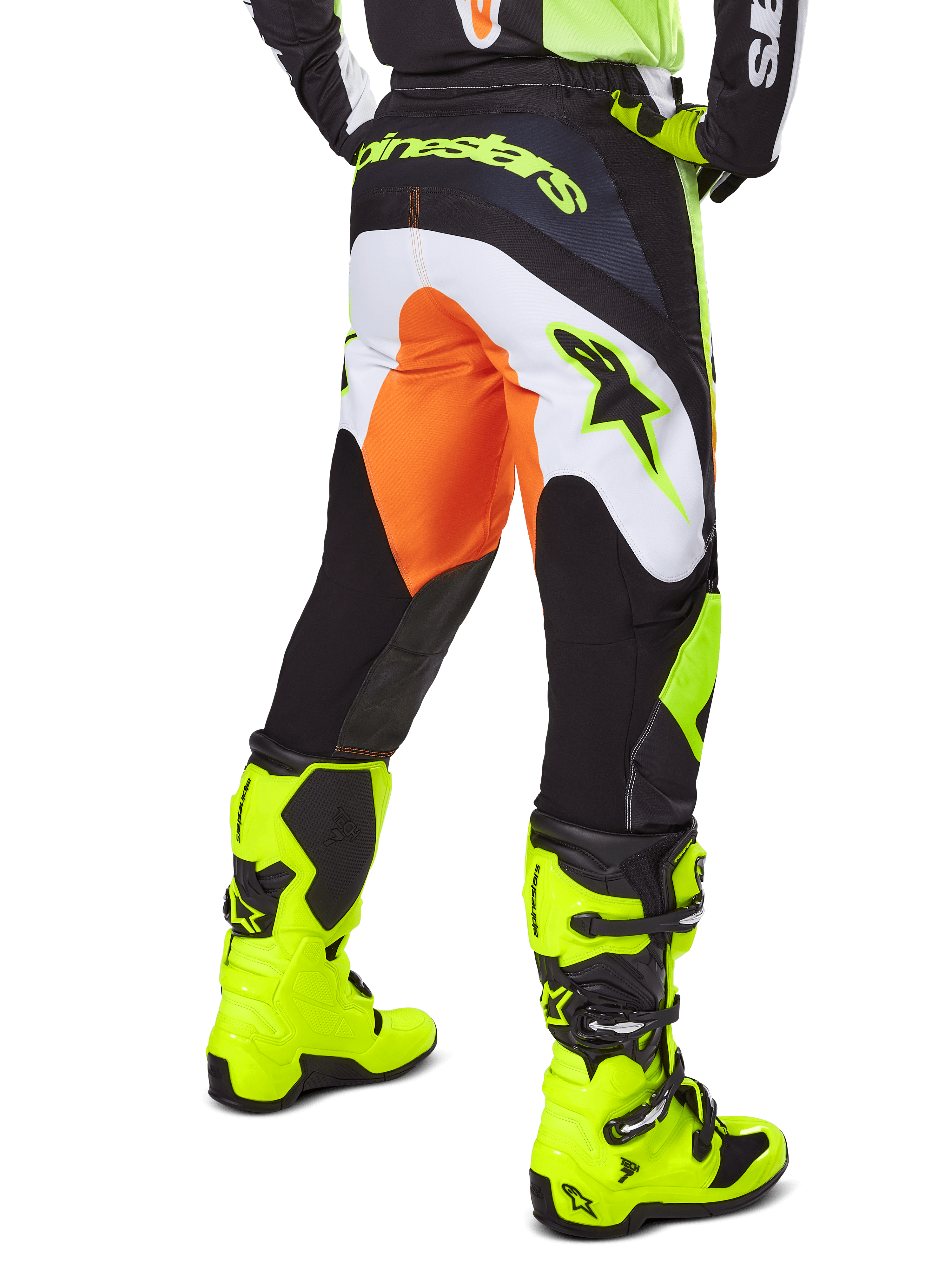 Alpinestars 2025 Fluid Wurx Pants, calças de motocross, amarelas e pretas com detalhes em laranja e branco, vista traseira, usadas com botas amarelas vibrantes a condizer, construção durável com logótipos em destaque para a prática de motocross