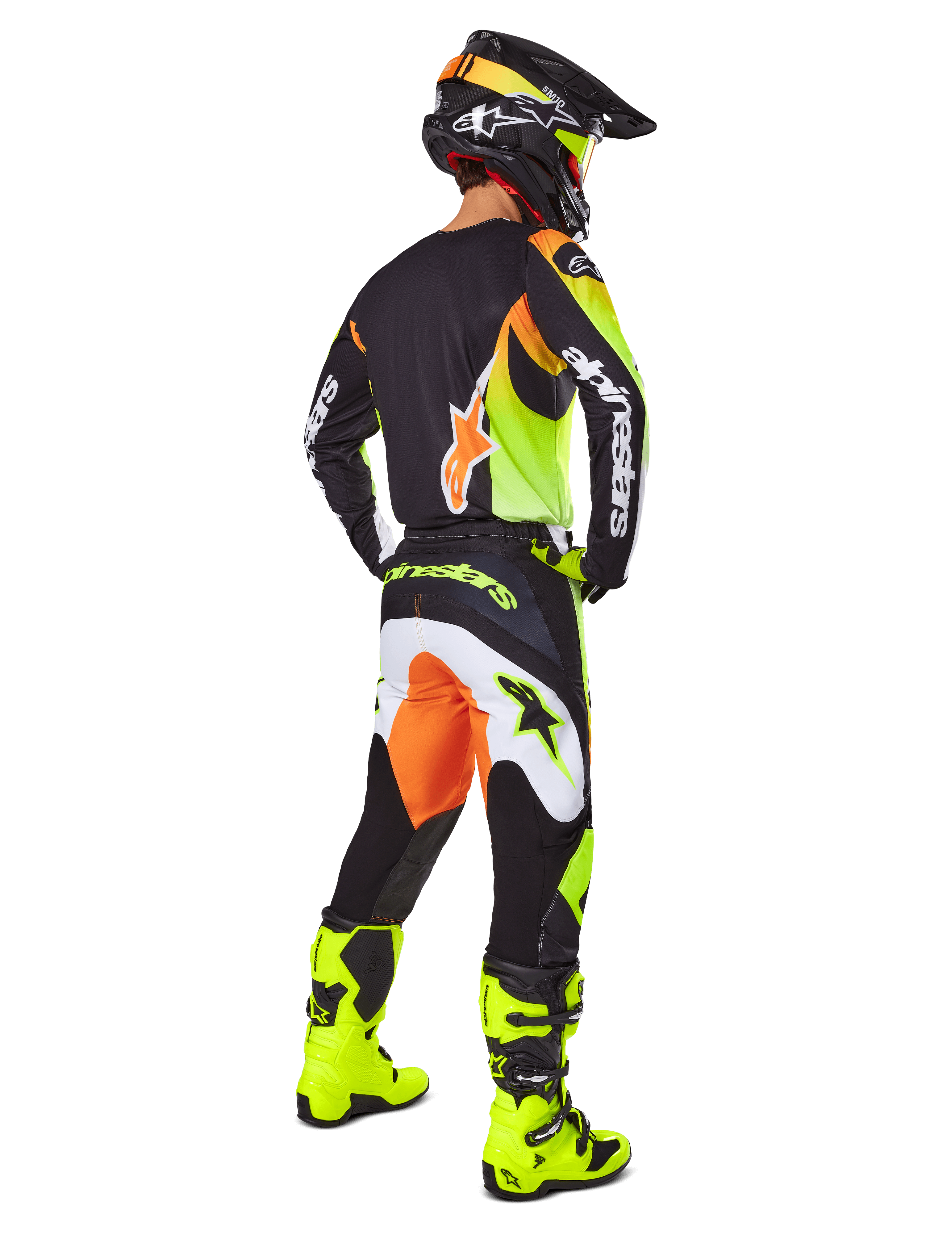 Piloto de motocross visto de costas a usar o conjunto de equipamento Alpinestars 2025 Fluid Wurx, camisola preta com pormenores amarelos e laranja, calças pretas a condizer com painéis brancos e laranja, botas amarelo vivo e capacete preto, equipamento completo de corrida off-road