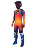 Piloto de motocross com equipamento de corrida completo, calças Alpinestars 2025 Fluid Wurx e camisola a condizer com gradiente multicolorido em laranja, vermelho e roxo, capacete preto com óculos vermelhos, botas azuis e pretas e luvas vermelhas e pretas; conjunto coordenado para todo-o-terreno