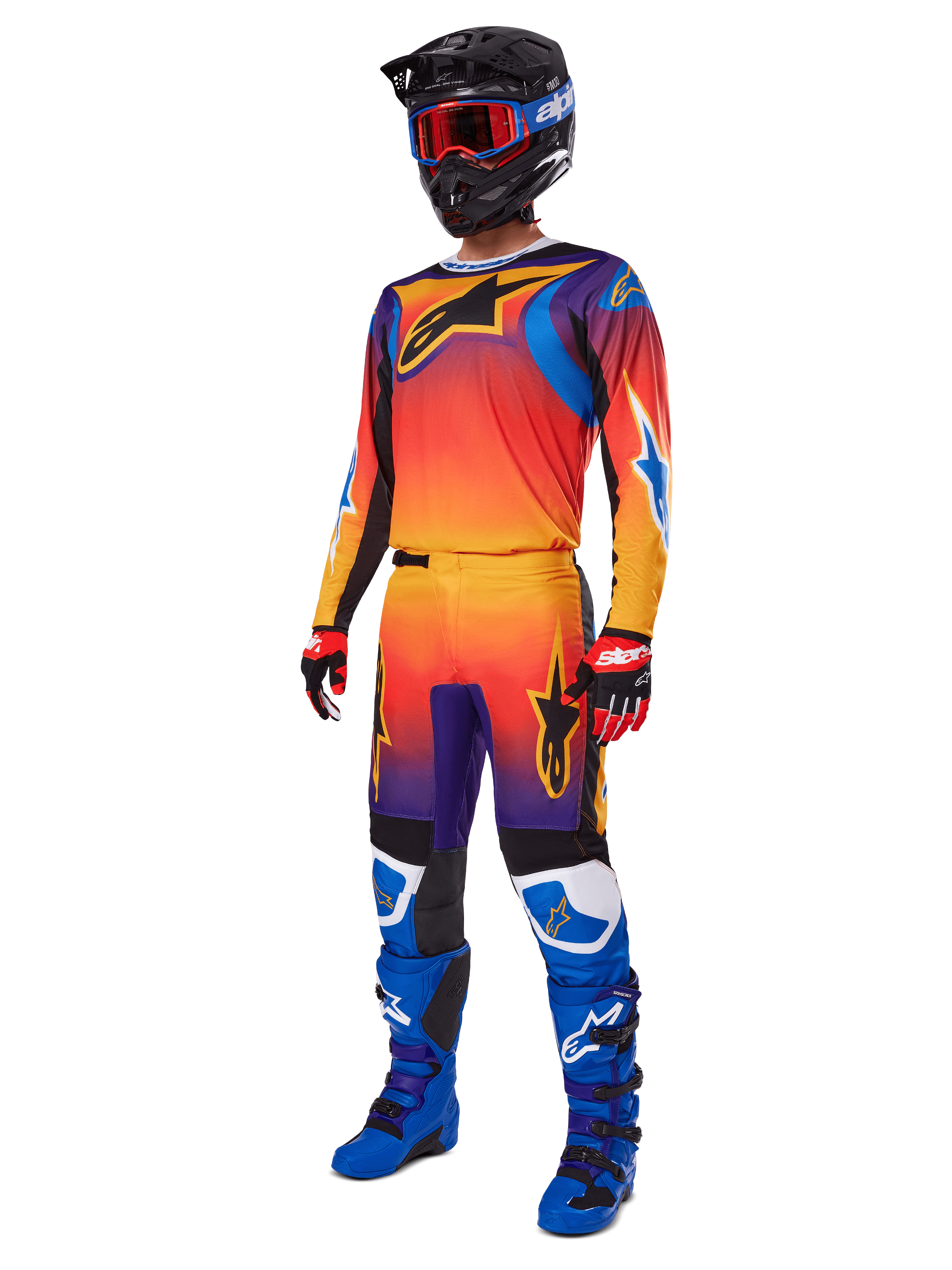 Piloto de motocross com equipamento de corrida completo, calças Alpinestars 2025 Fluid Wurx e camisola a condizer com gradiente multicolorido em laranja, vermelho e roxo, capacete preto com óculos vermelhos, botas azuis e pretas e luvas vermelhas e pretas; conjunto coordenado para todo-o-terreno