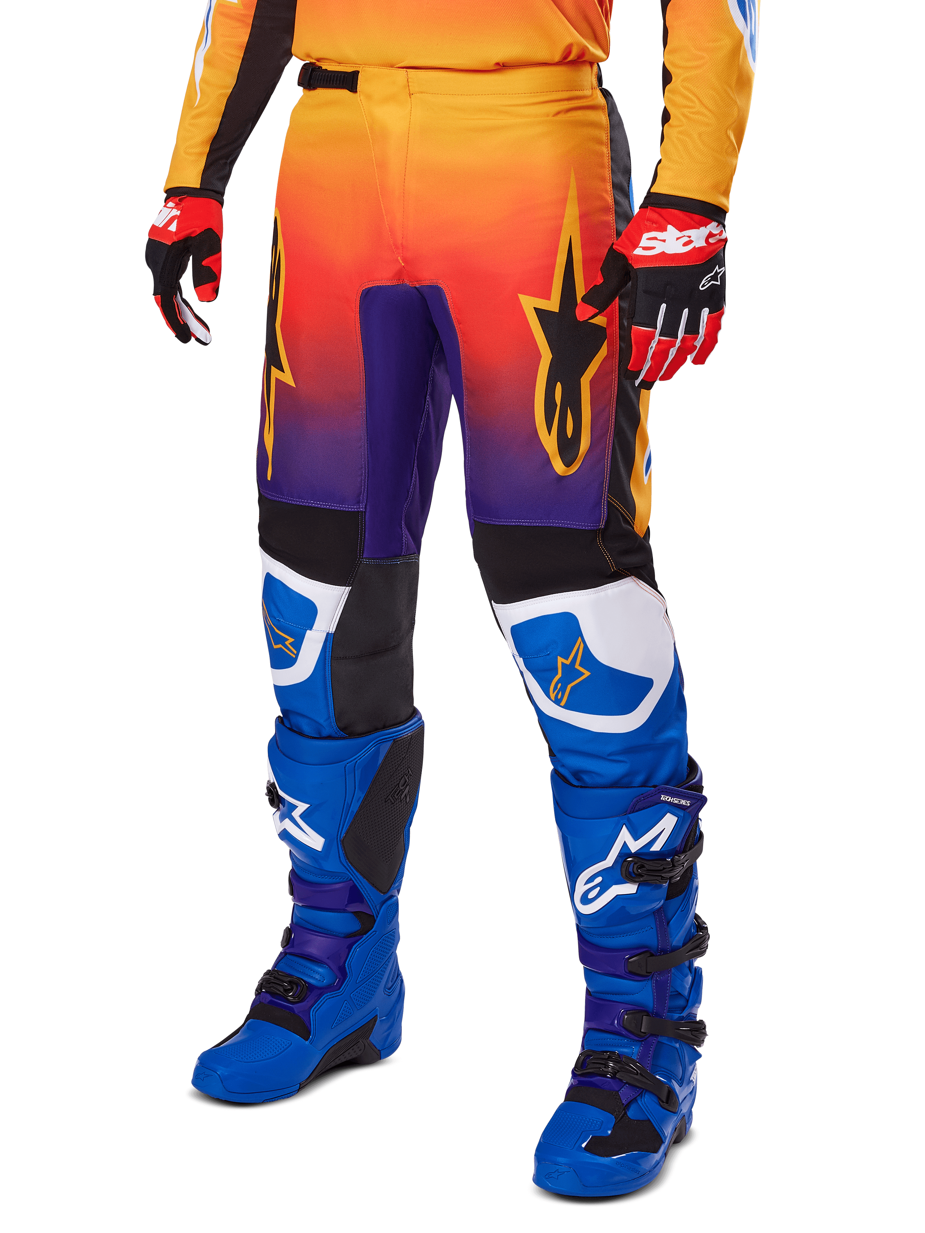 Calças Alpinestars 2025 Fluid Wurx, calças de motocross, gradiente multicolor de laranja, vermelho e roxo com painéis pretos e azuis, usadas com botas azuis e luvas vermelhas, com gráficos do logótipo de estrela e detalhes brancos nos joelhos, equipamento de performance durável para corridas todo-o-terreno