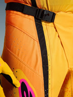 Alpinestars 2026 Techstar Nomur Pants, calças de motocross, cor de laranja, amarelo e rosa, pormenor da zona da cintura com o fecho de fivela magnética SX2, tira de ajuste preta e perfurações de ventilação cortadas a laser em material ripstop durável