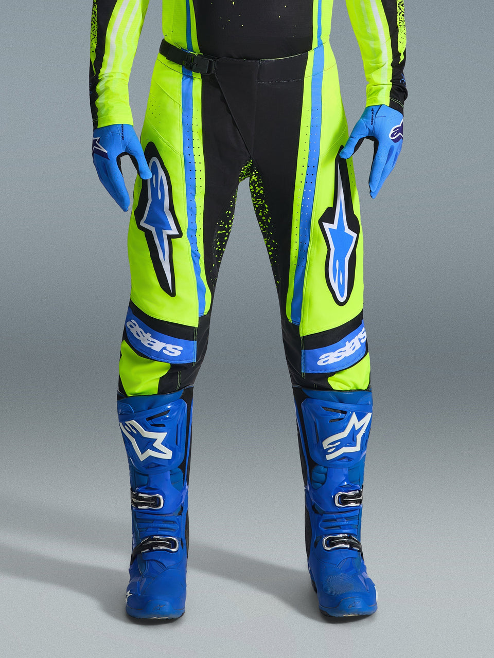 Alpinestars 2026 Techstar Nomur Pants, calças de motocross, amarelo néon e azul marinho com detalhes em azul, usadas com luvas e botas azuis a condizer, com logótipos Astars destacados nas coxas e design de alta performance para corridas fora de estrada.