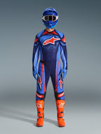 Conjunto de equipamento Alpinestars 2026 Techstar Nomur, piloto de motocross com kit de corrida completo, azul-escuro com detalhes em laranja e azul UCLA, camisola e calças a condizer com logótipos grandes, capacete azul e botas laranja vibrante, equipamento de competição todo-o-terreno coordenado.