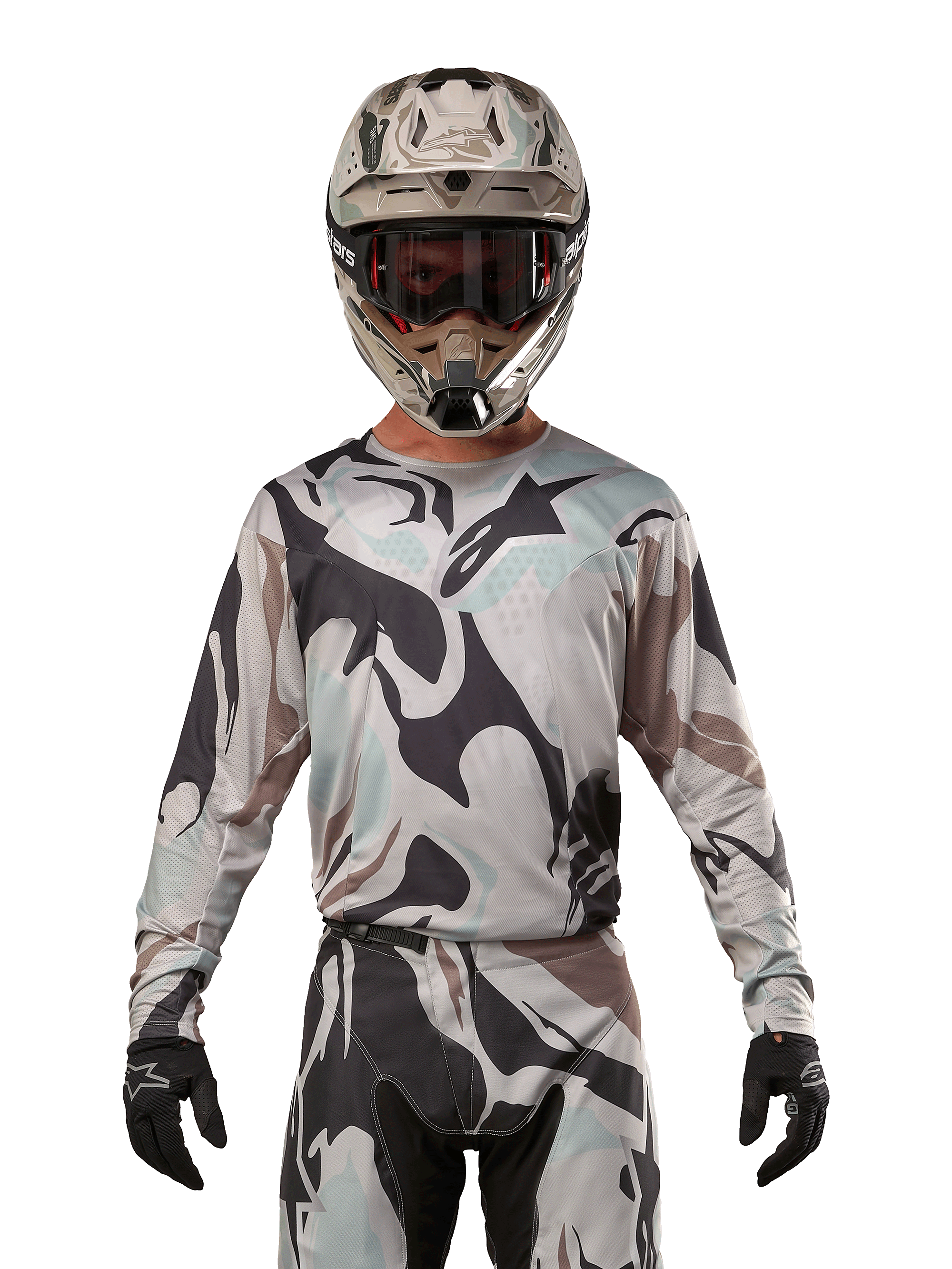 Alpinestars 2024 Racer Tactical Jersey, camisola de motocross, padrão camuflado Iron Camo Dust Gray, piloto a usar capacete e óculos a condizer com luvas pretas, equipamento técnico para corridas fora de estrada