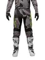 Alpinestars 2024 Racer Tactical Pants, calças de motocross, Cast Gray Camo Magnet, usadas com camisola camuflada a condizer, luvas pretas e botas brancas e pretas, com logótipos de estrela verde lima nas coxas e painéis extensíveis pretos, vista frontal de equipamento para condução todo-o-terreno