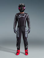 Alpinestars 2026 Fluid Apex Gear Set, fato de motocross, preto com detalhes cinzentos, camisola com grande logótipo Astars branco, calças coordenadas com logótipo em destaque, capacete preto com óculos rosa e botas vermelhas vibrantes, kit de corrida todo-o-terreno completo