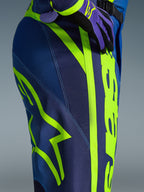 Alpinestars 2026 Fluid Apex Pants, calças de motocross, azul e amarelo fluo, vista aproximada da lateral e anca com branding Alpinestars em amarelo néon, material polifabric durável para condução off-road, parte de um conjunto de equipamento a condizer