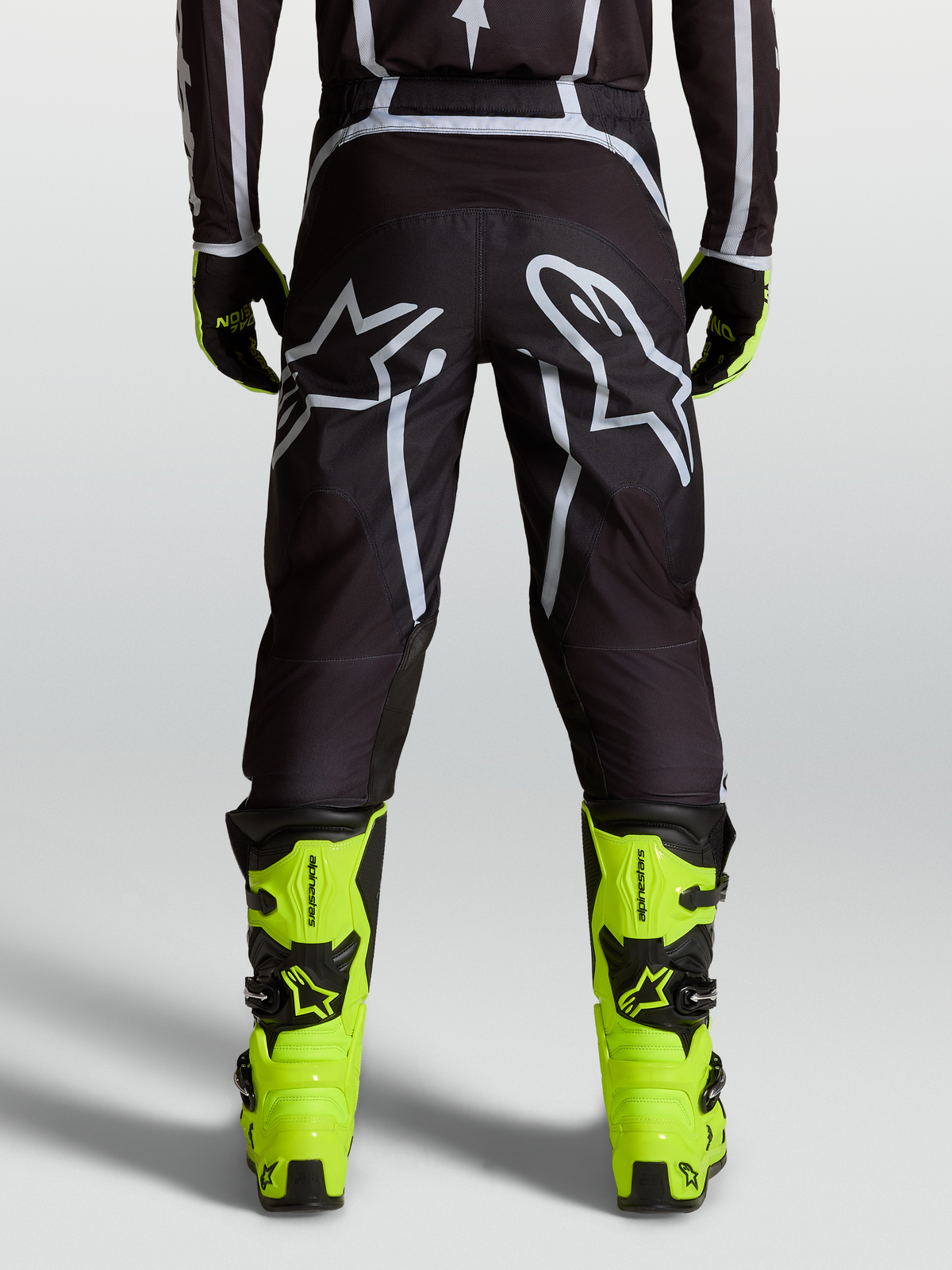 Alpinestars Fluid Apex V2 Pants, motocross riding pants in Black and Silver, featuring a pre-curved ergonomic fit and reinforced high-wear zones for off-road performance.
