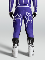 Alpinestars Calças Fluid Apex V2, calças de motocross para homem, azuis e brancas, construção robusta 600D, vista traseira no modelo com botas.