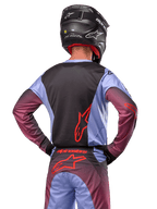 Motocross rider from the back wearing Alpinestars 2024 Racer Hoen gear, Lavan Purple and Black jersey with red logo, matching pants with red accents, black helmet, coordinated outfit for off-road racing