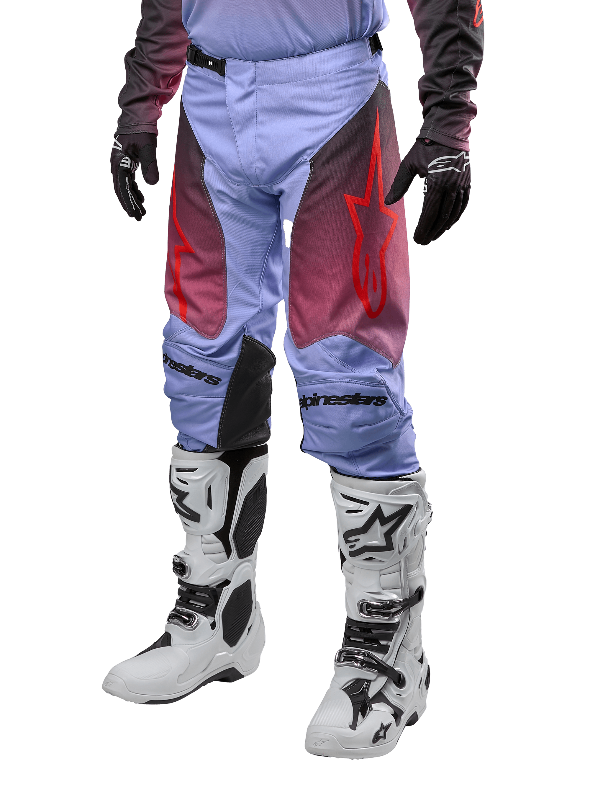 Alpinestars 2024 Racer Hoen Pants, calças de motocross, roxo Lavan e preto com grafismos vermelhos, logótipos de estrela vermelhos nas coxas e letras pretas nos joelhos, usadas com botas brancas e pretas e luvas pretas