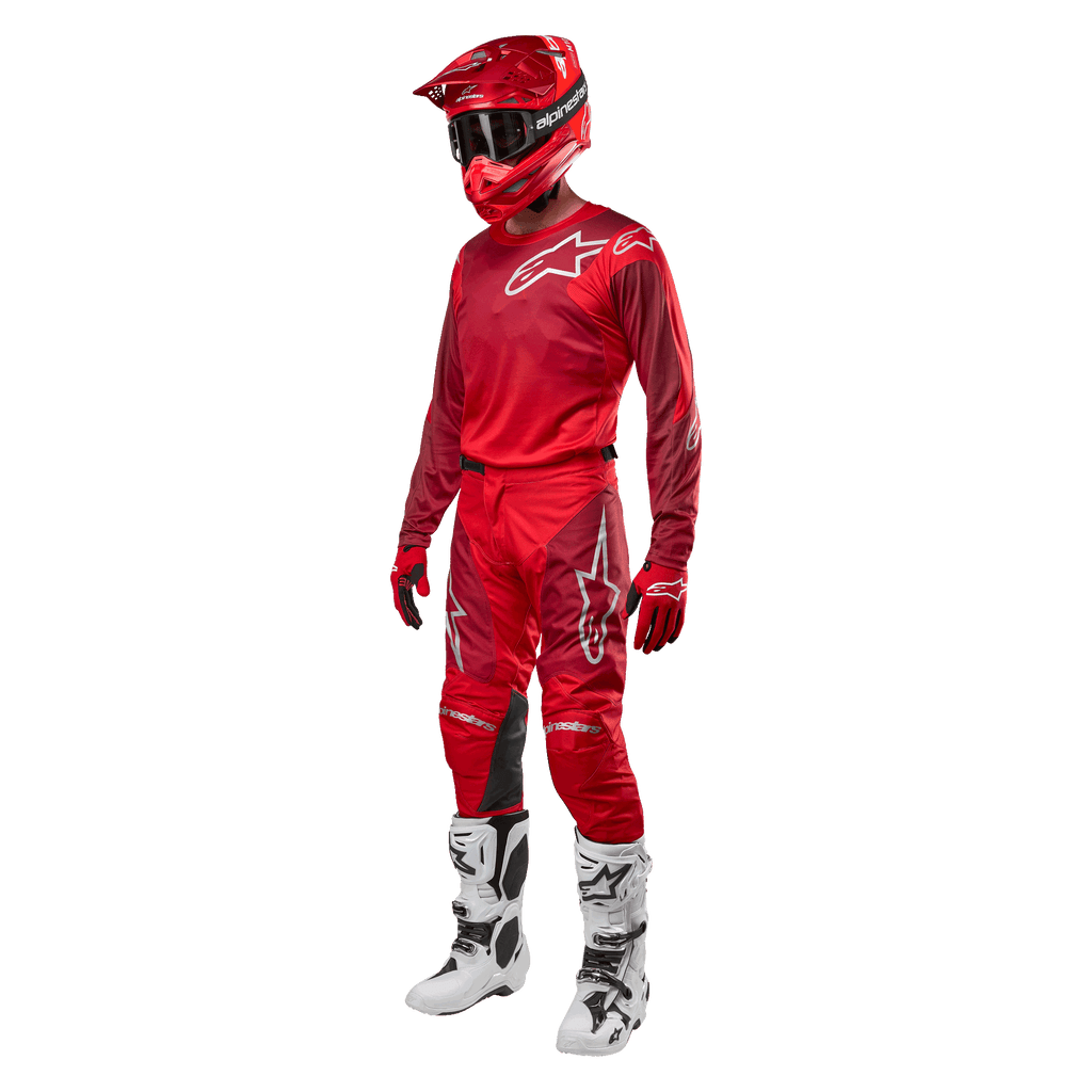 Piloto de motocross a usar equipamento completo de competição, calças e camisola Alpinestars 2024 Racer Hoen em Mars Red Burgundy, capacete vermelho, luvas vermelhas, e botas brancas e pretas, conjunto coordenado para corridas de todo-o-terreno