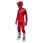 Piloto de motocross a usar equipamento completo de competição, calças e camisola Alpinestars 2024 Racer Hoen em Mars Red Burgundy, capacete vermelho, luvas vermelhas, e botas brancas e pretas, conjunto coordenado para corridas de todo-o-terreno