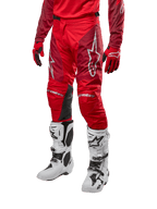 Calças Alpinestars Racer Hoen 2024, calças de motocross, Vermelho Mars e Borgonha, usadas com camisola e luvas vermelhas a condizer e botas brancas, com painéis de joelho em pele preta e logótipos brancos, equipamento técnico durável para todo-o-terreno