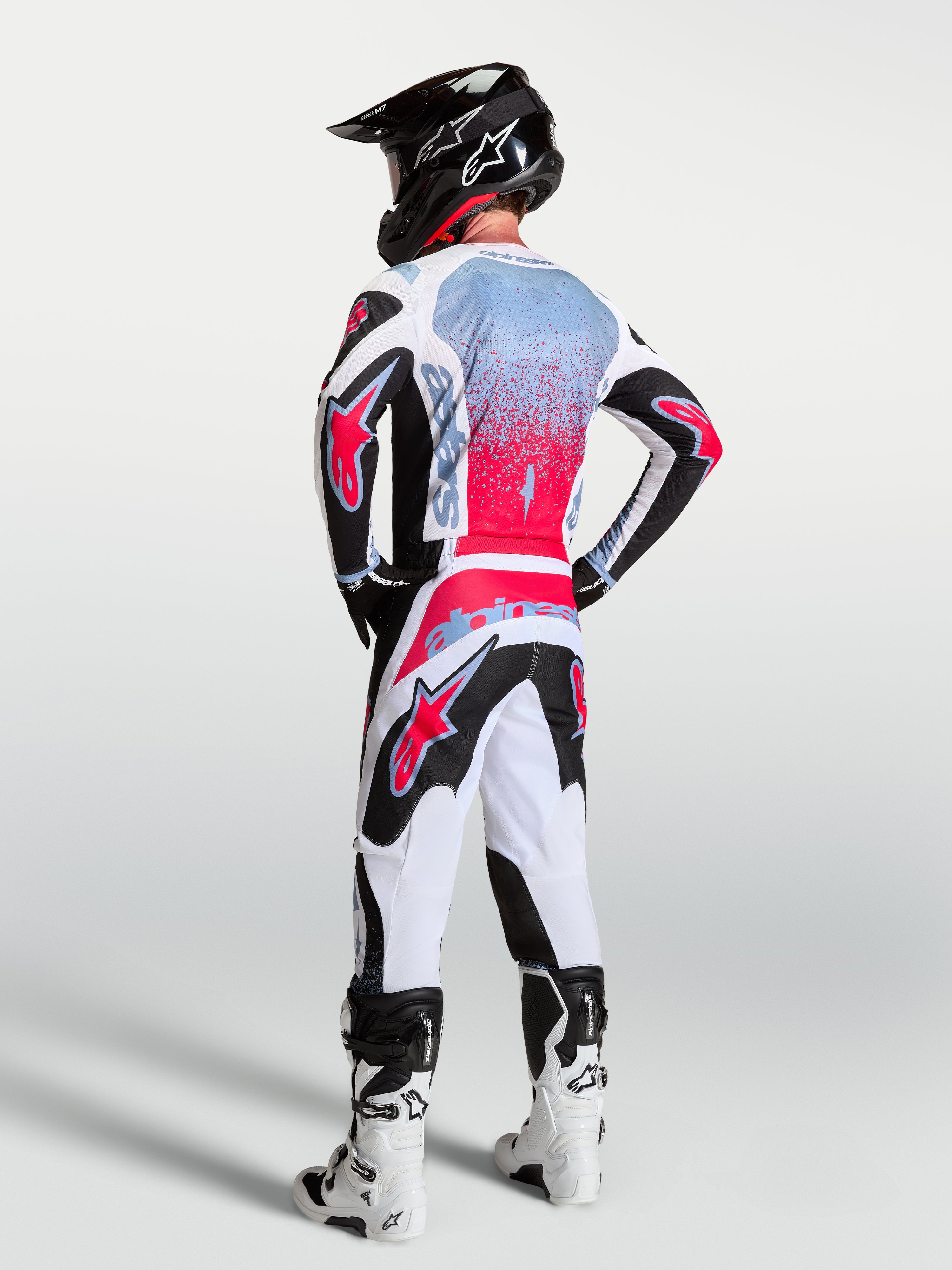 Alpinestars calças Fluid Drag, calças de motocross para homem, brancas e pretas com detalhes vermelhos, vista traseira no modelo.