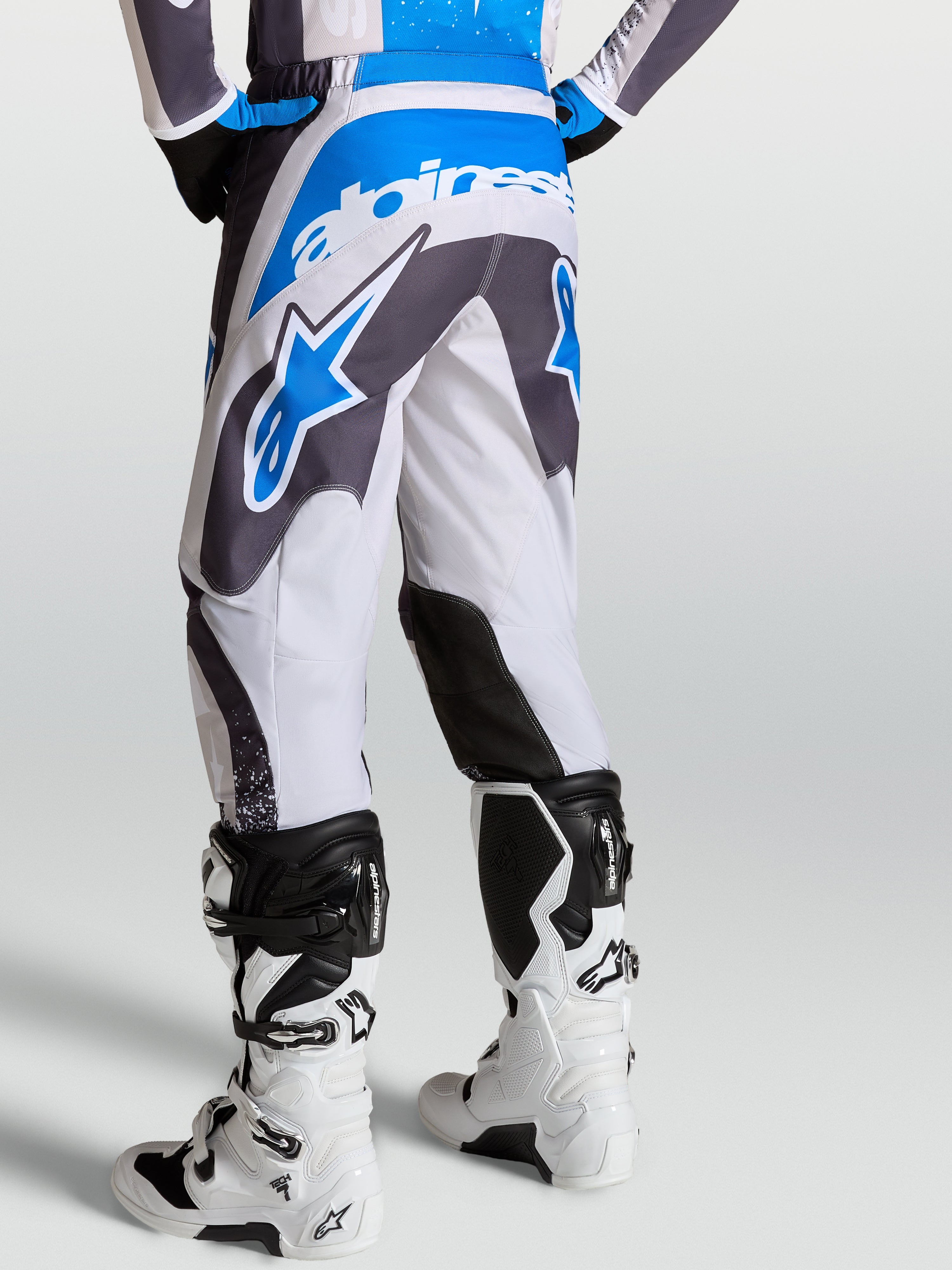 Calças Alpinestars Fluid Drag, calças de motocross em cinzento e azul, vista traseira com padrão ergonómico 3D.