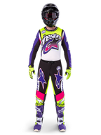 Motocross rider wearing complete racing gear, Limited Edition Supertech Dirt Studios jersey and pants in white, purple, and yellow fluo, black helmet with goggles, purple and white boots, coordinated vibrant outfit for off-road motocross racing