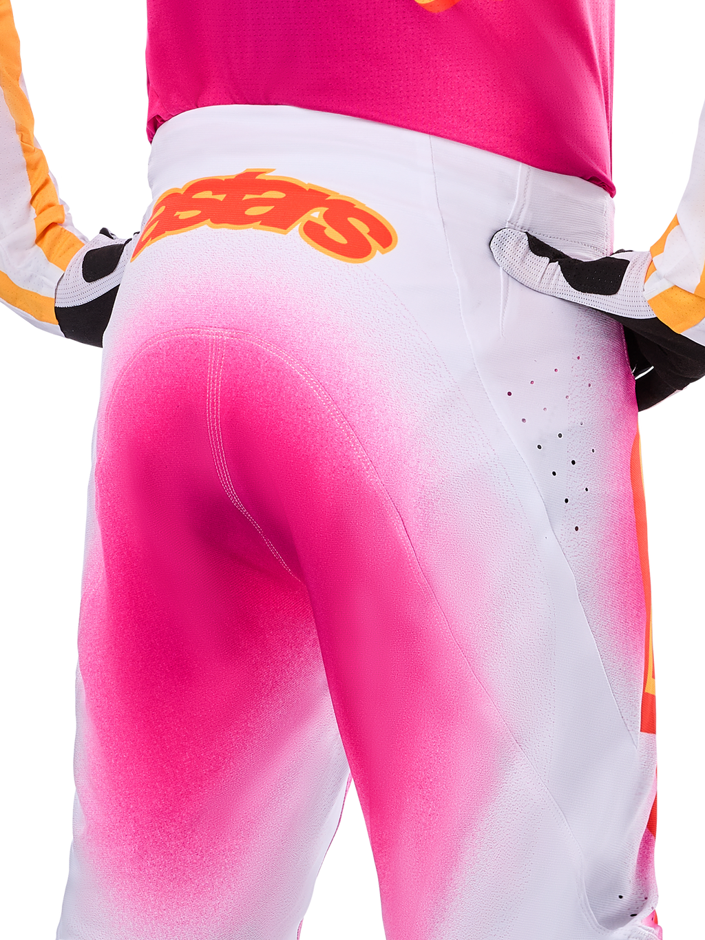 Alpinestars Limited Edition Supertech AFD MIG Pants, Motocross Pants, Pink Fluo and White with a spray-paint fade effect, large orange Alpinestars logo on the rear waistband, close-up view showing athletic fit and ventilation perforations.