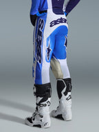 Alpinestars 2026 Racer Air Portl Pants, calças de motocross, azul e branco, vista traseira, design arrojado em azul e branco com logótipo de grandes dimensões no assento e na lateral, joelhos internos reforçados em pele de cabra, usadas com botas de motocross brancas e pretas para performance off-road