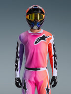 Camisola Alpinestars 2026 Racer Air Portl, camisola de motocross, gradiente vibrante de rosa, roxo e laranja, usada com um capacete e óculos a condizer, com um logótipo de estrela preto grande no peito, construção em malha respirável, equipamento de performance para corridas off-road