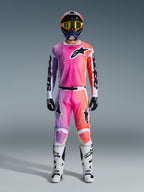 Piloto de motocross a usar a camisola 2026 Racer Air Portl e calças a condizer, apresentando um gradiente rosa, roxo e laranja com logótipos Alpinestars pretos, botas de corrida brancas, luvas pretas e capacete multicolor, equipamento de corrida off-road profissional