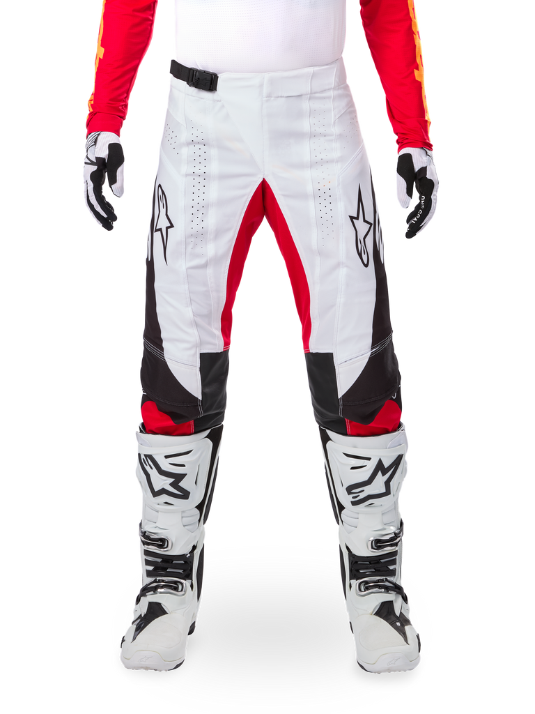 Calças Alpinestars Techstar Deep Edição Limitada, calças de motocross, pretas, brancas e vermelho vivo, usadas com camisola vermelha a condizer, luvas e botas brancas e pretas, com painéis frontais brancos, detalhes vermelhos no interior das pernas, painéis laterais pretos, logótipos Alpinestars nas coxas e pormenores perfurados a laser para ventilação.