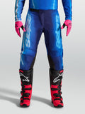 Alpinestars Calças Fluid Kepler, calças de motocross para homem, azuis, em polifabric 600D leve com ajuste ergonómico, modelo equipado com luvas cor-de-rosa e botas de mota vermelhas e pretas.