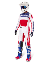 Calças Alpinestars Limited Edition Techstar Fortitude, conjunto de equipamento de motocross, em vermelho, branco e azul, usadas com camisola a condizer, capacete branco, óculos azuis e botas azuis e vermelhas, fato de corrida profissional coordenado para competição de todo-o-terreno
