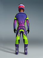 Alpinestars 2026 Supertech Vista Pants, Motocross Pants, Yellow Purple and Black, rear view of a motocross rider in a complete racing gear set with a purple gradient jersey and purple boots, vibrant athletic design for professional off-road racing