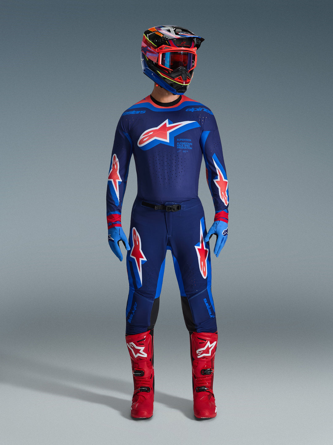Conjunto de Equipamento Supertech Vista 2026, fato de corrida de motocross completo, camisola e calças azul-escuro com logótipos de estrelas vermelhas e brancas, capacete multicolorido com óculos vermelhos, luvas azul-claro e botas vermelhas vibrantes, equipamento de MX de nível profissional