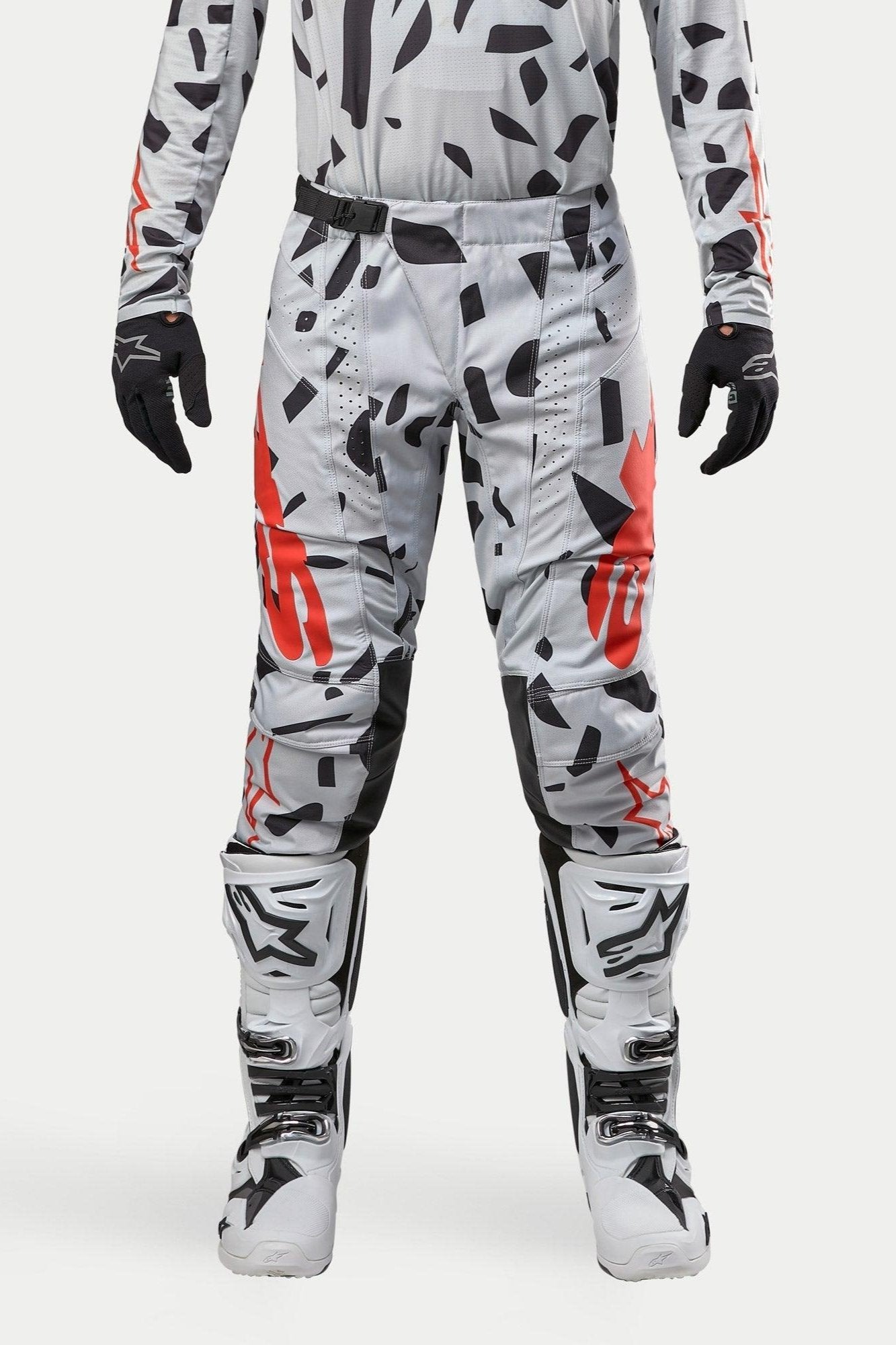 Calças Alpinestars 2024 Techstar Rantera, calças de motocross, cinzento Haze Gray Camo, usadas com jersey a condizer, luvas pretas e botas brancas, com padrão de manchas pretas e logótipo Alpinestars em vermelho, design durável para corridas de todo-o-terreno
