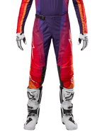 Alpinestars 2024 Techstar Pneuma Pants, calças de motocross roxas, cor de laranja e azuis, com detalhes em vermelho e logótipo branco, equipamento de proteção para todo-o-terreno, modelo a usar botas e luvas brancas.