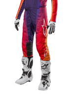 Alpinestars 2024 Techstar Pneuma Pants, calças de motocross em roxo profundo, laranja e azul com gradiente vibrante, logótipo da estrela em branco, joelheiras reforçadas, acompanhadas por botas de motocross brancas e luvas, equipamento de proteção para todo-o-terreno