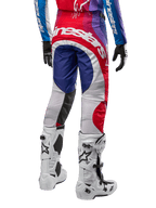 Alpinestars 2024 Techstar Pneuma Pants, calças de motocross, azul, vermelho e branco, vista traseira usadas com camisola a condizer e botas brancas, com logótipo branco em destaque no assento e painéis multicor, vestuário profissional de motocross