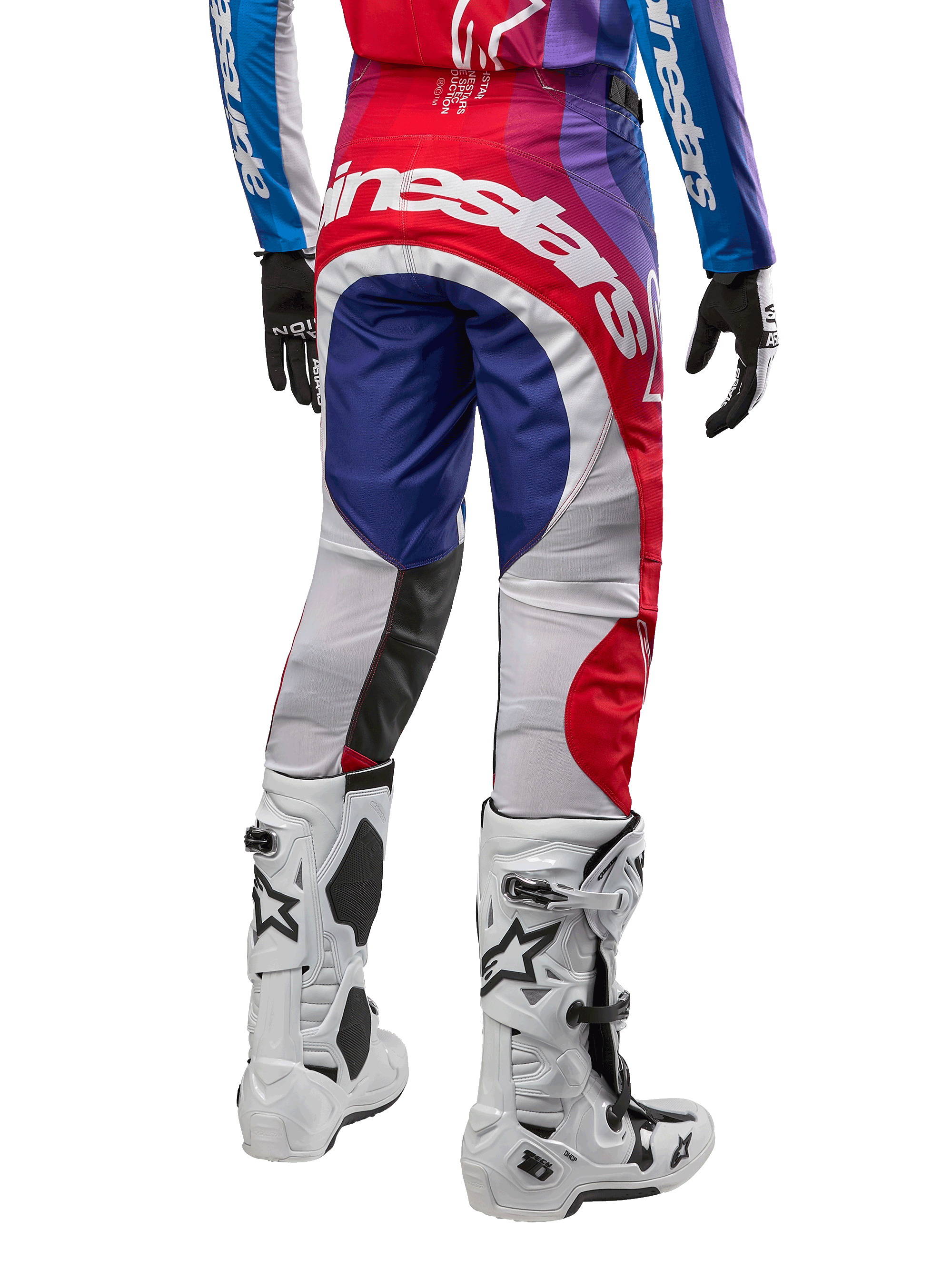 Alpinestars 2024 Techstar Pneuma Pants, calças de motocross, azul, vermelho e branco, vista traseira usadas com camisola a condizer e botas brancas, com logótipo branco em destaque no assento e painéis multicor, vestuário profissional de motocross