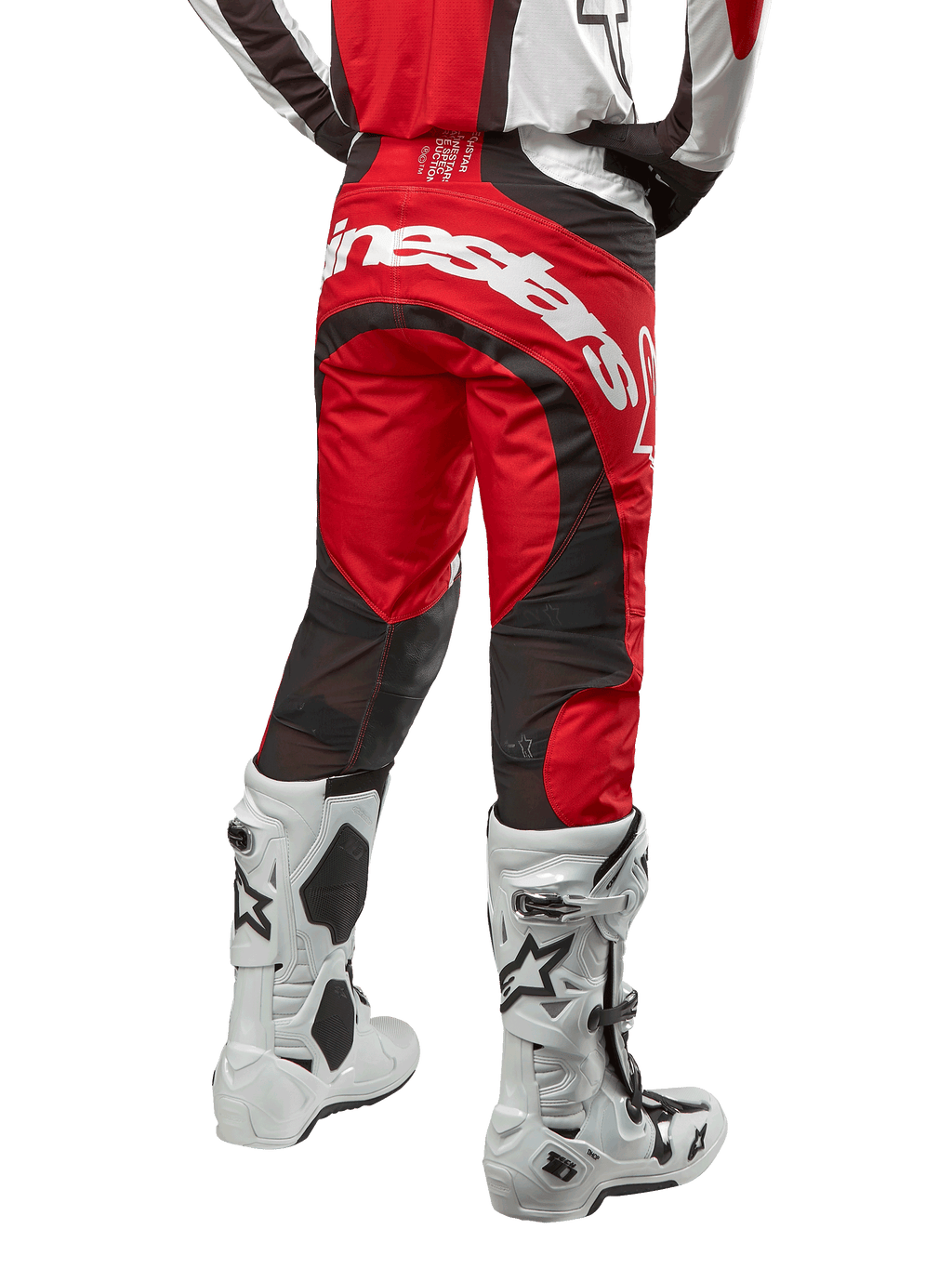 Alpinestars 2024 Techstar Ocuri Pants, calças de motocross, Vermelho Mars, branco e preto, vista traseira com grande logótipo Alpinestars branco no assento, painéis de ventilação em malha preta, usadas com botas de motocross brancas e pretas, design atlético de corte de corrida para condução todo-o-terreno