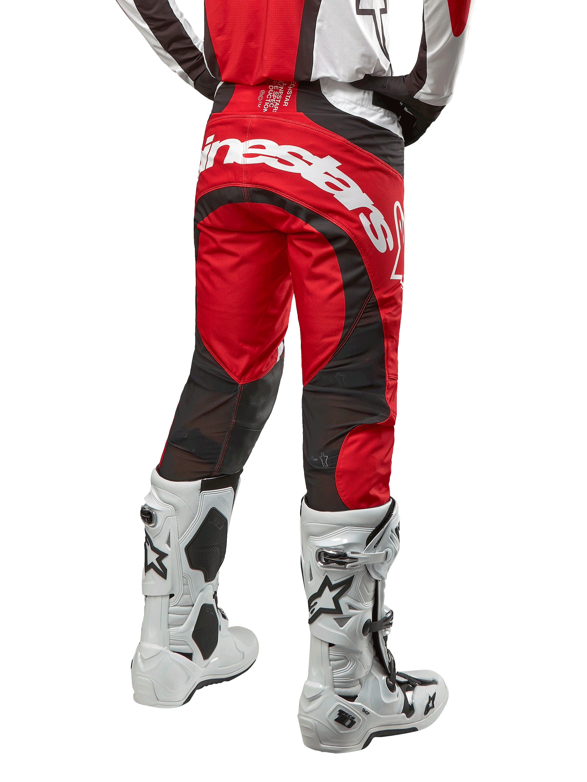 Alpinestars 2024 Techstar Ocuri Pants, calças de motocross, Vermelho Mars, branco e preto, vista traseira com grande logótipo Alpinestars branco no assento, painéis de ventilação em malha preta, usadas com botas de motocross brancas e pretas, design atlético de corte de corrida para condução todo-o-terreno