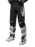 Alpinestars 2024 Racer Hana Pants, calças de motocross pretas com detalhes e logótipos brancos, joelheiras reforçadas, acompanhadas por botas de motocross brancas e luvas pretas, equipamento de alto desempenho para todo-o-terreno