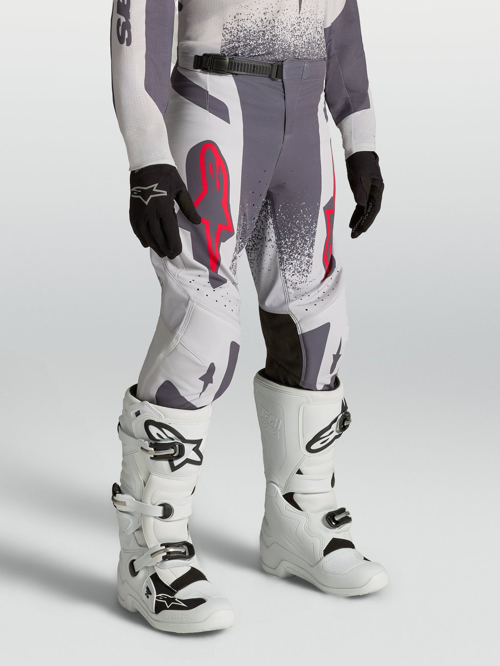 Alpinestars Calças Supertech Swan Juventude, calças de motocross cinzentas e lilás com detalhes em vermelho fluorescente.