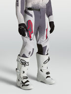 Alpinestars Calças Supertech Swan Juventude, calças de motocross cinzentas e lilás com detalhes em vermelho fluorescente.