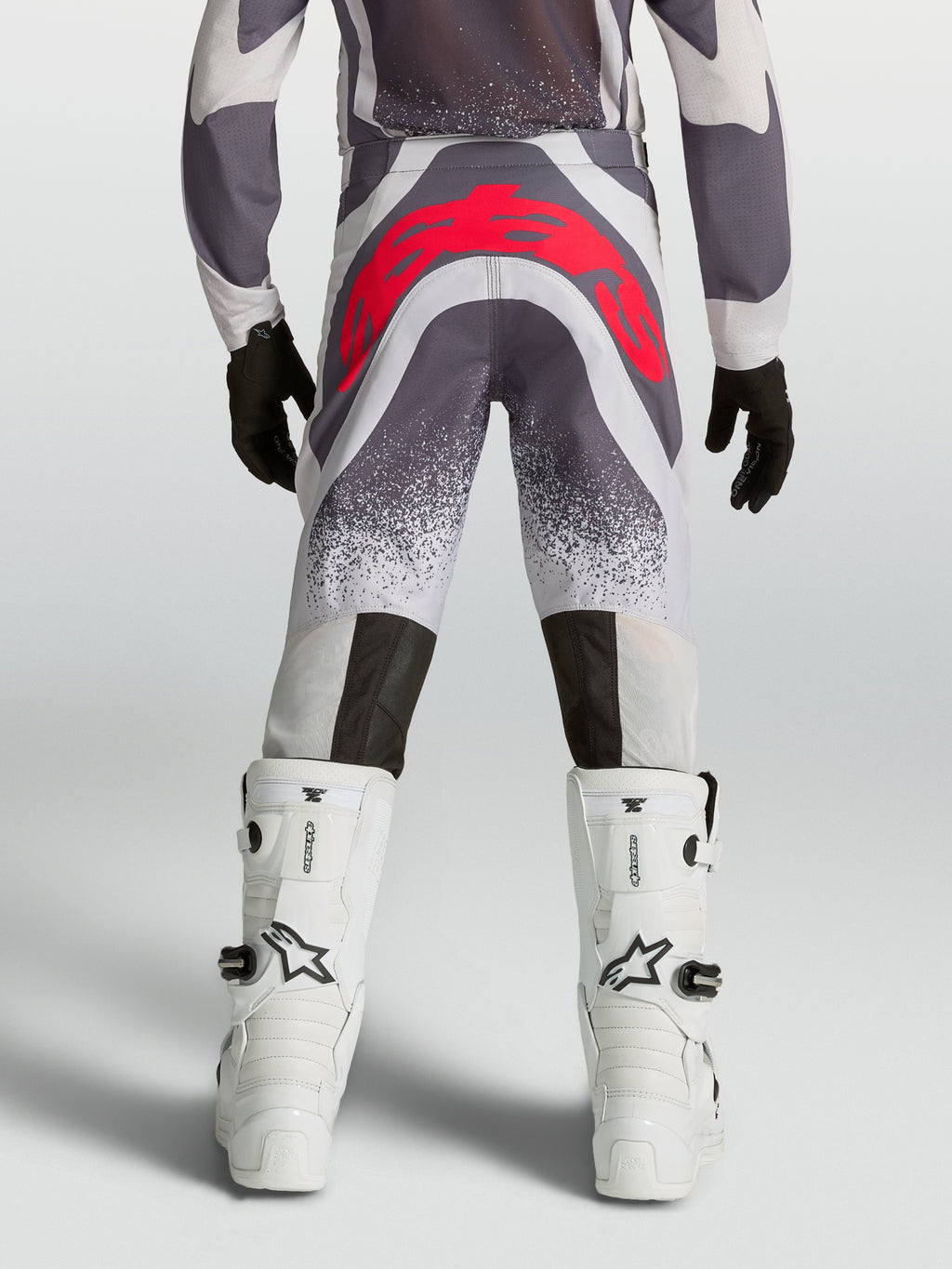 Alpinestars Supertech Swan, calças de motocross para juventude, cinzentas e vermelhas fluo, vista traseira, ajuste atlético premium com reforço no assento