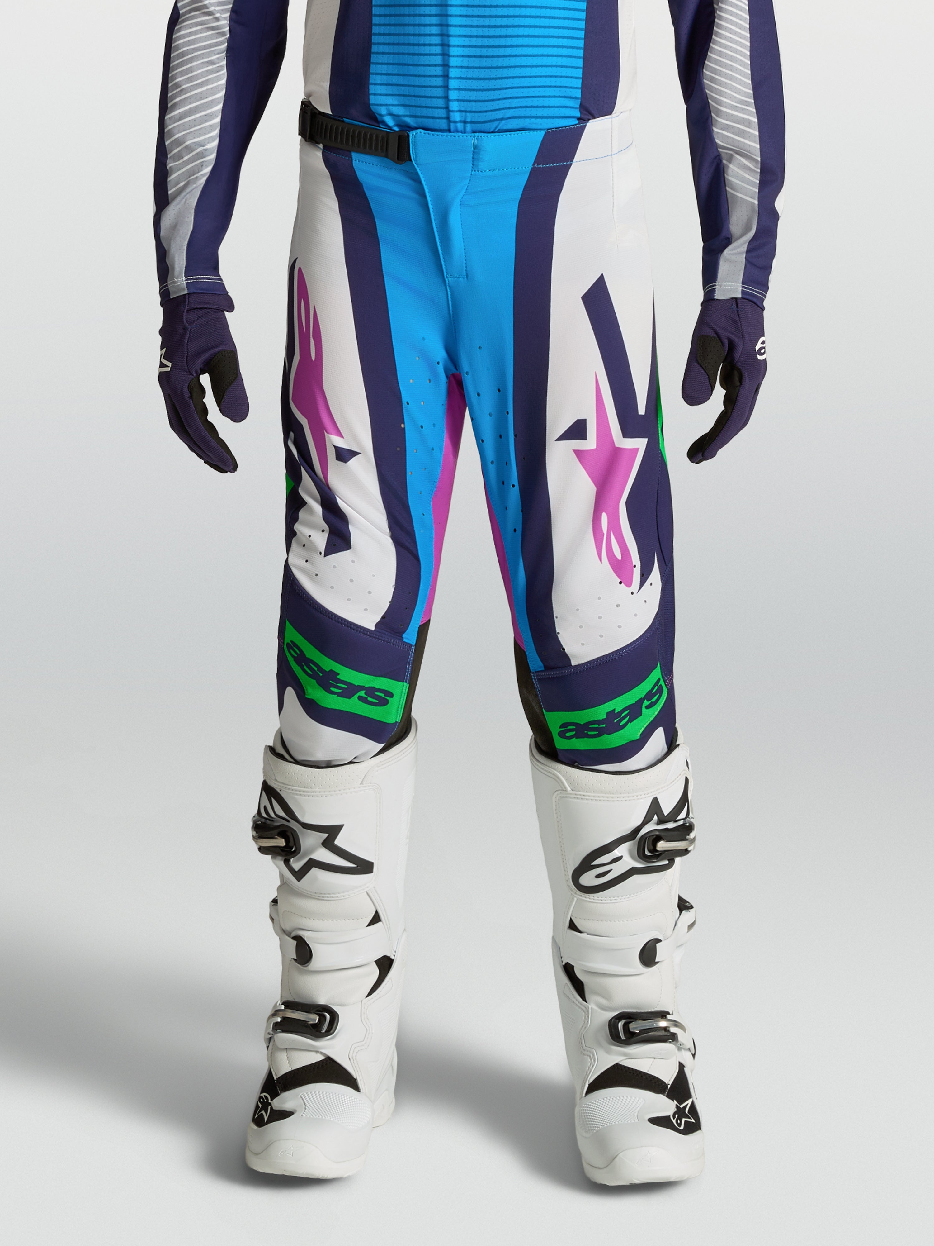 Calças Alpinestars Supertech Maven Juventude, brancas e azuis com detalhes verde fluorescente e ajuste atlético.