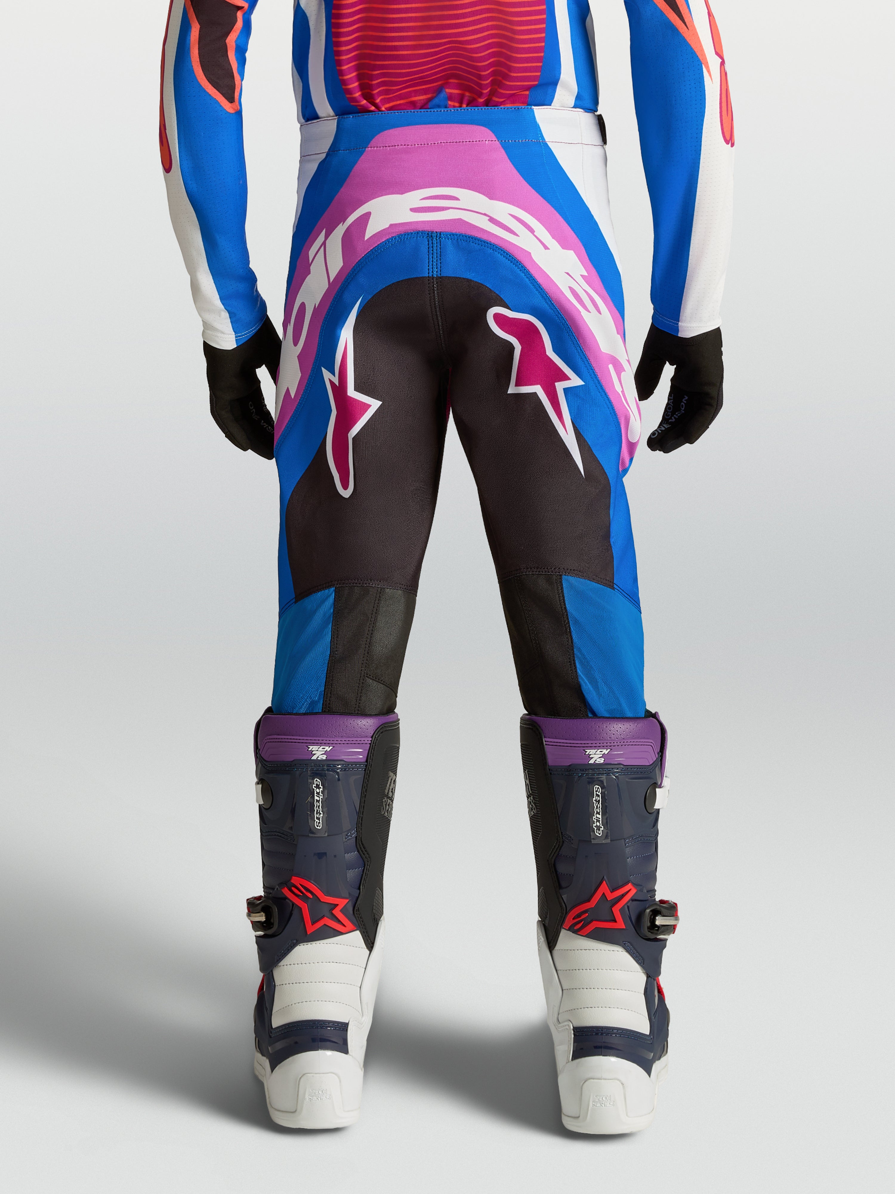 Alpinestars Supertech Maven, calças de motocross para juventude, azuis e rosa coral, com assento reforçado e ajuste atlético.