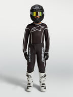 Alpinestars calças Fluid Apex V2 Juventude, conjunto de motocross preto e prateado com camisola e botas brancas.