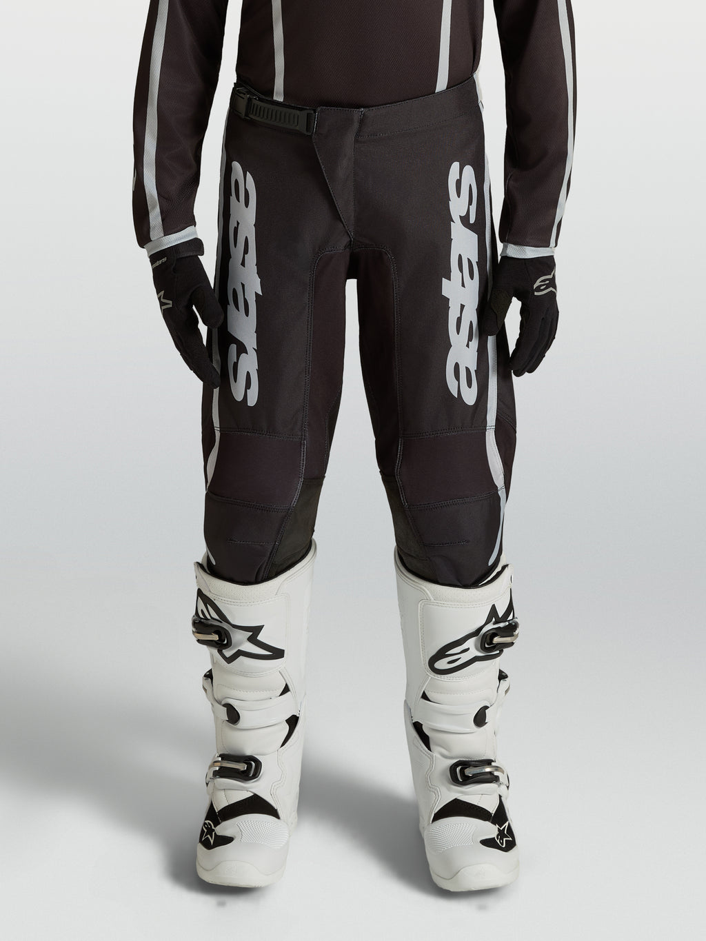 Alpinestars Fluid Apex V2, calças de motocross para juventude, pretas e prateadas, em polifabric 600D com pernas pré-curvadas.