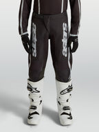 Alpinestars Fluid Apex V2, calças de motocross para juventude, pretas e prateadas, em polifabric 600D com pernas pré-curvadas.
