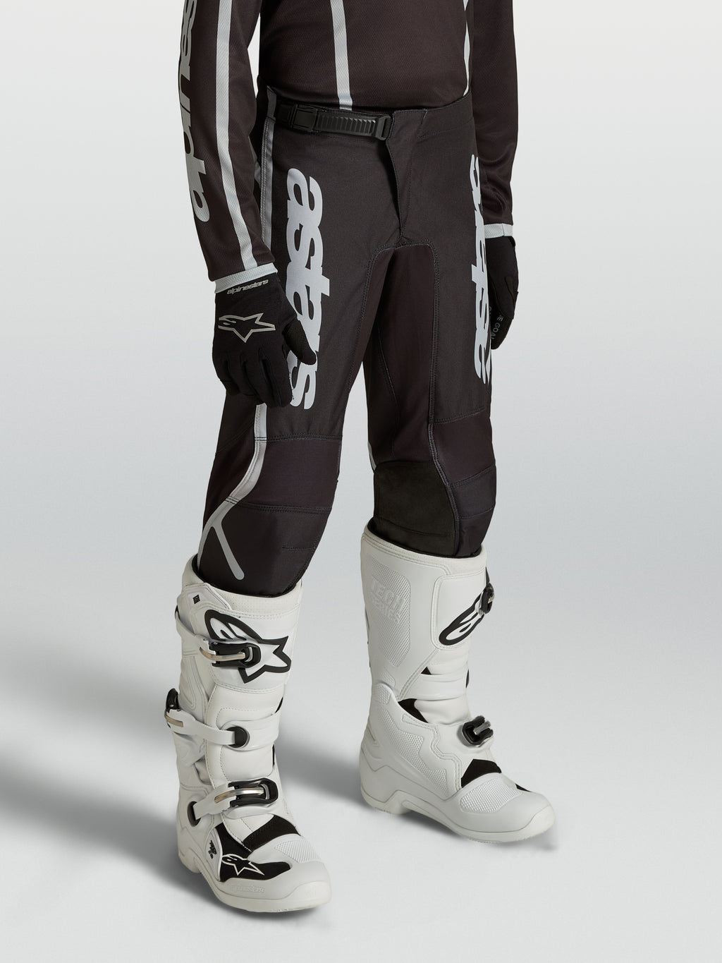 Calças Alpinestars Fluid Apex V2 Juventude para jovens pilotos, pretas e prateadas, com ajuste ergonómico pré-curvado.