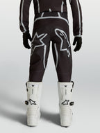 Alpinestars Calças Fluid Apex V2 Juventude, calças de motocross pretas e prateadas, vista traseira com logótipos de estrela.