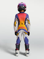 Alpinestars Calças Fluid Drag Juventude 2027, calças de motocross para jovens, azuis, brancas e amarelas, vista traseira de piloto em performance off-road.